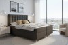 Gemütliches Schlafzimmer-Ambiente mit dunklem Boxspringbett und Blick auf die Stadt
