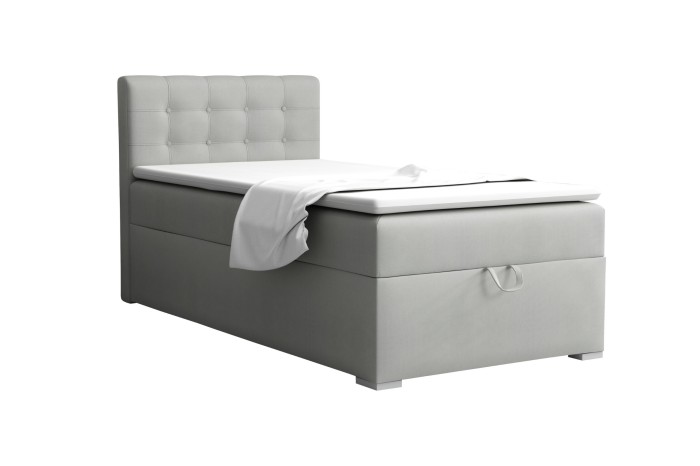 Light grey boxspring bed single bed with quilted headboard against a white background.