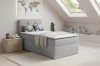 Graues Boxspringbett im modern eingerichteten Dachzimmer mit hellem Teppich.