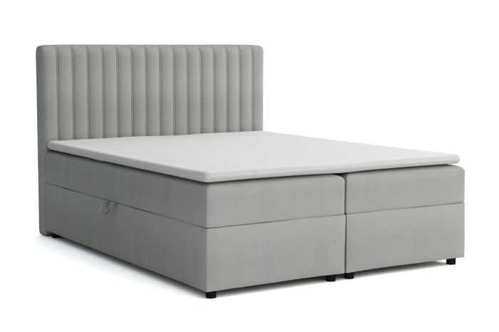 Grijs boxspringbed met geribbeld hoofdbord, vrijstaand op wit.