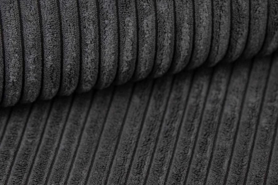 Detailansicht der Rippenstruktur eines dunkelgrauen Cordstoffs.