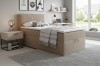 Gezellige slaapkamer met beige boxspringbed, nachtkastje en grijs tapijt.