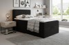 Modern bedroom design with black box-spring bed, nightstand, and light-coloured rug.