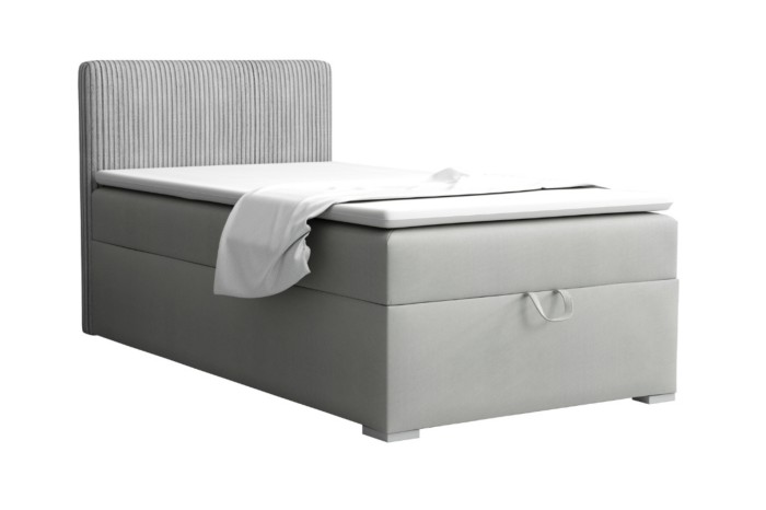 Lichtgrijs boxspringbed met geribbelde hoofdsteun en bedbak op een witte achtergrond.