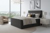 Dunkelgraues Boxspringbett mit modernem Kopfteil in stilvollem Schlafzimmer.