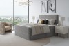 Hellgraues Boxspringbett mit Textur in minimalistischem Raum mit Stadtblick.