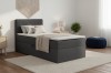 Anthrazitfarbenes Boxspringbett im hellen Schlafzimmer-Ambiente.