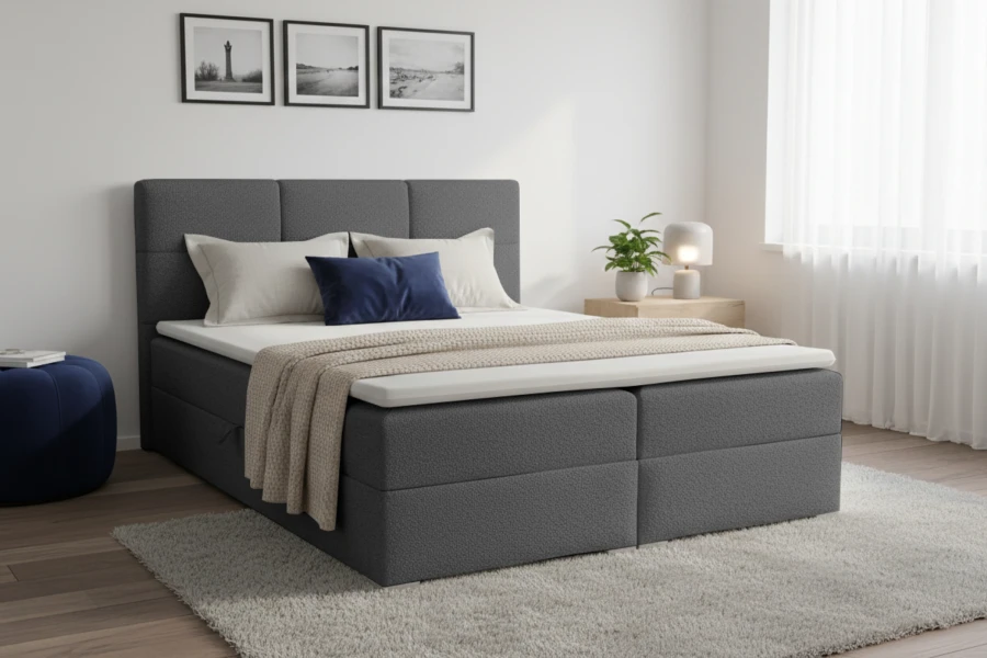 Dunkelgraues Boxspringbett in gemütlichem Schlafzimmer mit blauen Farbakzenten und weichem Teppich.