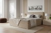 Elegantes beiges Boxspringbett mit gestreifter Struktur in hellem Raum.