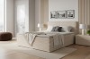 Beiges Boxspringbett mit geripptem Stoffbezug vor Holzpaneelen.
