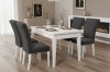 Elegante Essgruppe mit weißem Tisch und dunkelgrauen Samtstühlen vor modernem Kamin.