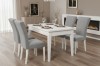 Elegantes Esszimmer mit weißem Tisch, grauen Samtstühlen und modernem Wandkamin.