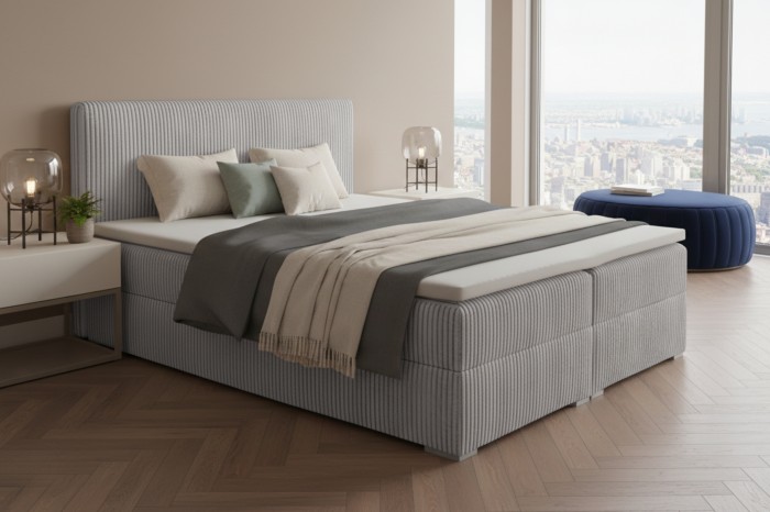 Lichtgrijs boxspringbed met cord-optiek en panoramisch uitzicht over de stad.