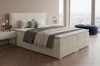 Gemütliches beiges Boxspringbett mit Cord-Struktur und weichen Kissen im modernen Design.