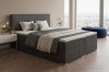 Modernes Boxspringbett in Dunkelgrau mit geripptem Stoffbezug und Nachttisch.