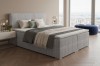 Modernes hellblaues Boxspringbett mit geripptem Kopfteil in einem stilvollen Schlafzimmer mit Stadtblick.