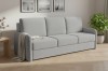 Graues 3-Sitzer Sofa mit Bouclé-Stoff in hellem Wohnzimmer-Ambiente.