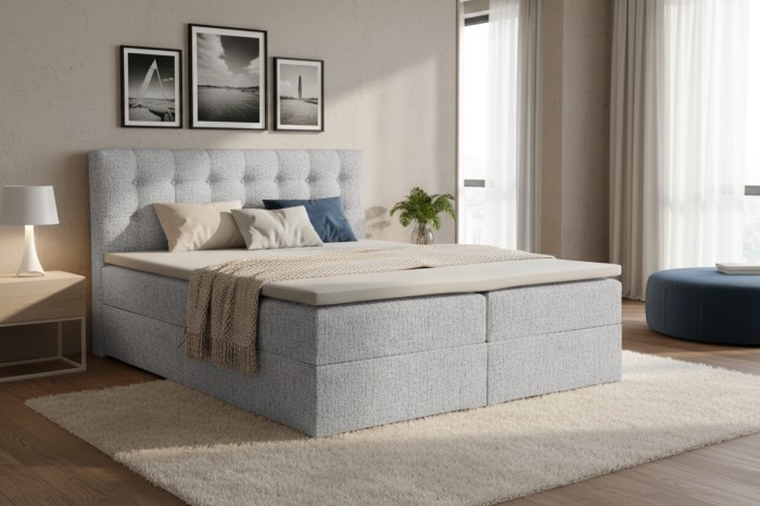 Gemütlich eingerichtetes Schlafzimmer mit einem hellgrauen Boxspringbett und Deko.