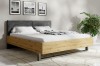 Modernes Doppelbett in Eiche-Optik mit grauem Polsterkopfteil und weißer Bettwäsche.