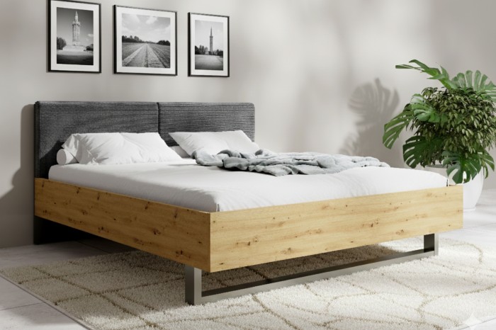 Modernes Bett mit Holzrahmen und grauem Polsterkopfteil in einem hell eingerichteten Schlafzimmer.
