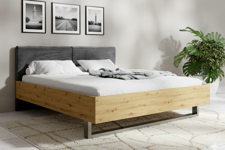 Modernes Bett mit Holzrahmen und grauem Polsterkopfteil in einem hell eingerichteten Schlafzimmer.
