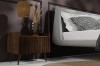 Eleganter Holz-Nachttisch neben einem grauen Polsterbett im Schlafzimmer.