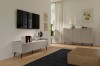 Modernes Wohnzimmer mit beigem TV-Lowboard, Sideboard und Wandfernseher in hellem Ambiente.
