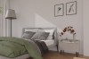 Gemütliches Schlafzimmer mit grauem Bett, grüner Decke und hellem Design-Nachttisch.