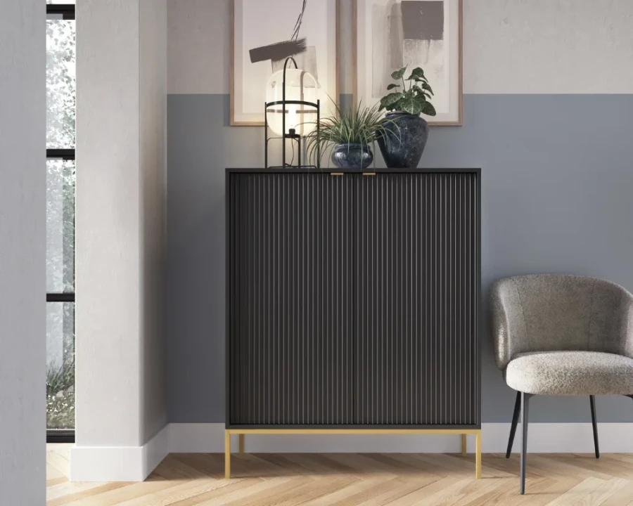 Moderner schwarzer Schrank im Wohnzimmer mit Pflanzen dekoriert, neben einem grauen Sessel.