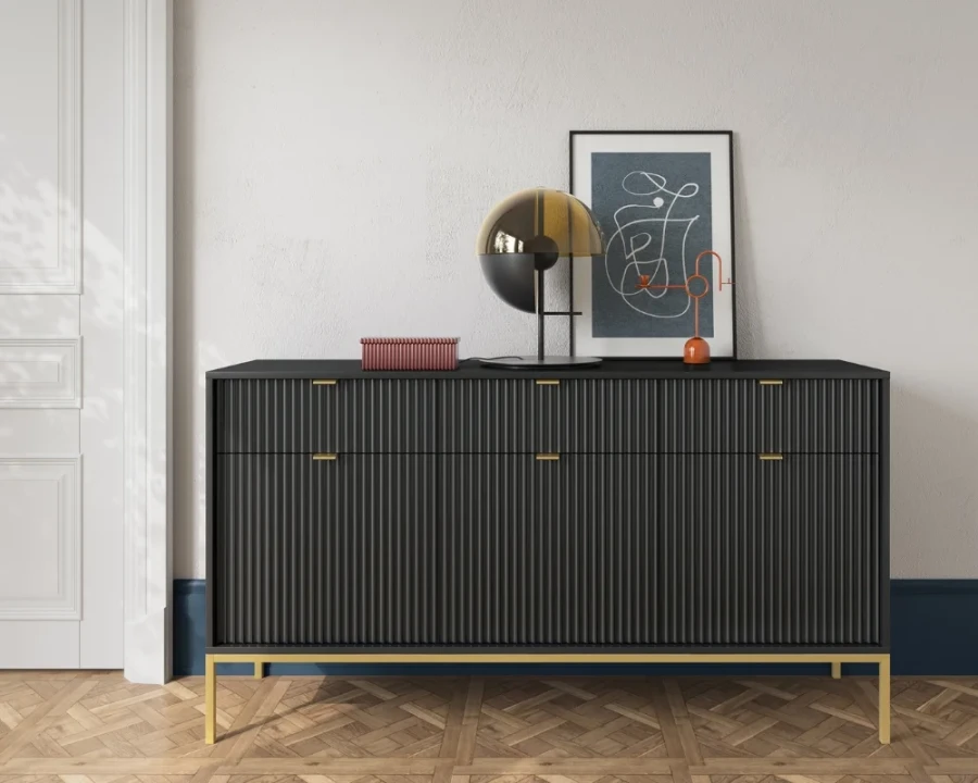 Schwarzes Sideboard mit Rillenfront, goldenen Beinen und dekorativer Lampe.