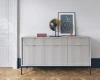 Modernes Sideboard in Hellgrau mit Riffeloptik, Designerlampe und Bild auf Parkettboden.