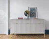 Detailansicht Sideboard mit Riffelstruktur, Goldbeinen und moderner Dekoration vor weißer Wand.