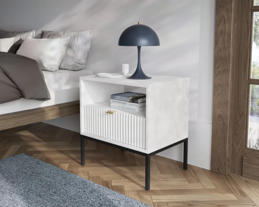 Weißer Nachttisch im eingerichteten Schlafzimmer mit Lampe und Büchern als Dekoration.
