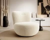 Moderner Bouclé-Sessel in Cremeweiß in einem minimalistisch gestalteten Wohnzimmer.