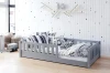 Kinderzimmer-Inspiration mit grauem Juniorbett, gemusterten Kissen und Wanddeko.