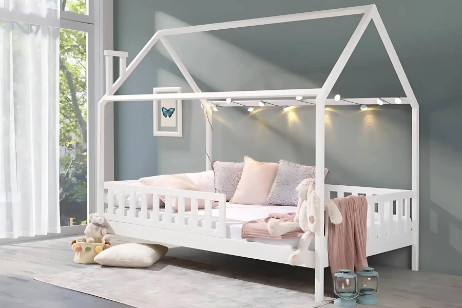 Cosily decorated white house bed for children with fairy lights in the children's room.