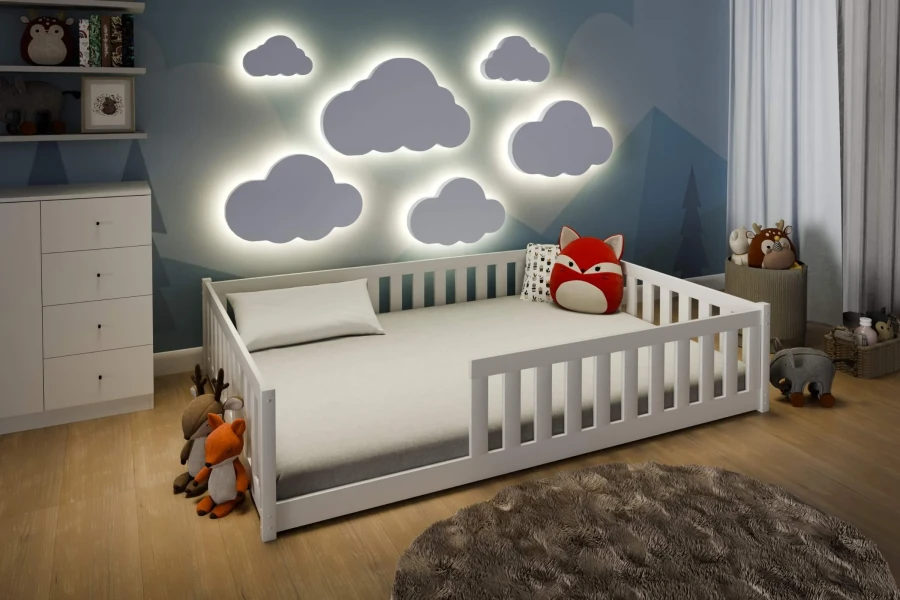 Weißes Kinderbett mit Rausfallschutz in gemütlichem Kinderzimmer mit Wolken-Wandleuchten.