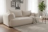 Gemütliches beige-farbenes Sofa in hellem, modernen Wohnzimmer mit Teppich und Pflanzen.