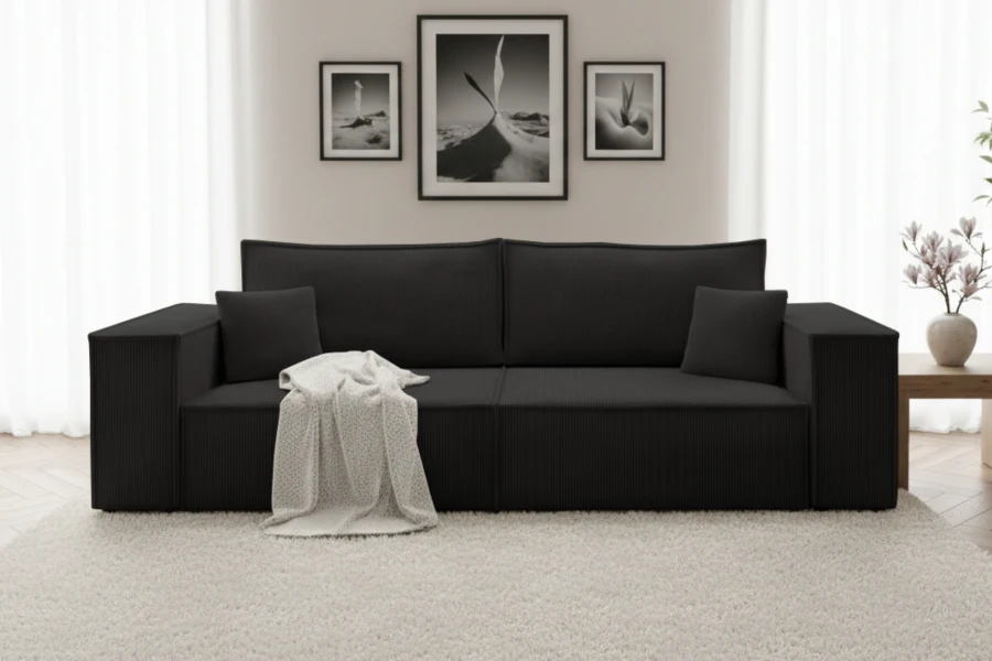 Schwarzes Cordsofa im Wohnzimmer mit hellem Teppich und Wandbildern