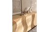Modernes Sideboard mit gewellter Holzfront und eleganter Dekoration.