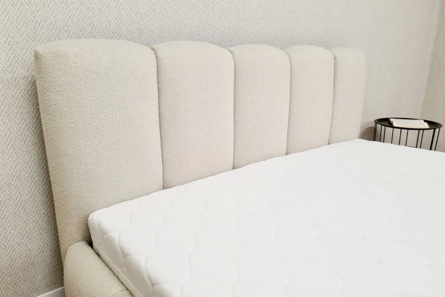 Detailansicht des gepolsterten Kopfteils in Beige mit weichem Bouclé-Stoffbezug.