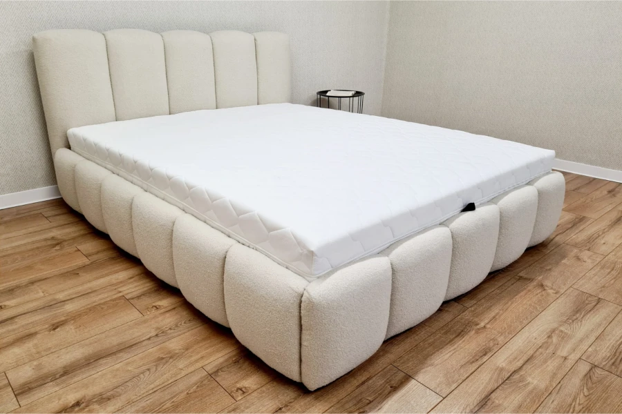 Zeitloses Polsterbett in Beige mit weicher Bouclé-Struktur auf hellem Holzboden.