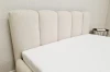 Detailaufnahme eines gepolsterten Kopfteils in Beige mit eleganten vertikalen Paneelen.