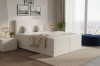 Modernes beiges Boxspringbett in Cord-Optik vor einem großen Fenster.