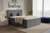Dunkelgraues Boxspringbett mit Cord-Oberfläche vor einer Fensterfront mit Panoramaaussicht.