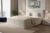 Modernes Boxspringbett in Beige mit strukturiertem Kopfteil im hellen Schlafzimmer.