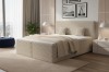 Gemütliches beige Boxspringbett in modernem Schlafzimmer mit Ausblick und Design-Leuchten.