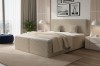 Beiges Boxspringbett mit gepolstertem Kopfteil im hellen Schlafzimmer