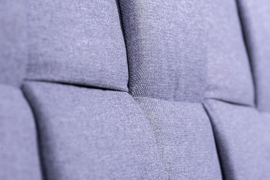 Nahaufnahme blauer Stoffbezug mit quadratischer Steppung für Polsterbett-Kopfteil.