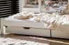 Detailansicht eines weißen Kinderbettes mit zwei praktischen Schubladen für Stauraum unter dem Bett.